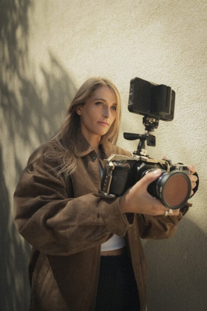 A woman holding a camera in front of a wall